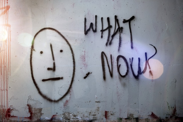 the phrase "what now" written on a wall